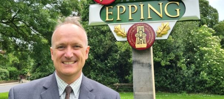 Dr Neil Hudson standing in front of Epping sign 